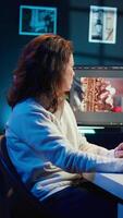 Vertical Upbeat videographer reviewing footage and selecting scenes, trimming using specialized software applications and editing tools. Smiling editor working for media company in editing room, camera B video