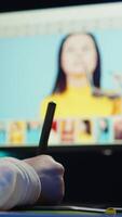 Vertical Photo editor using graphic tablet to retouch photographs with editing software on, zooming in to find spots that need correcting. Photographer in creative workplace adjusting images, camera B video