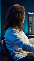 Vertical Videographer using editing software to assemble footage into cohesive final result while enjoying cup of coffee. Specialist color correcting clips while drinking hot beverage, camera A video