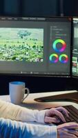 Vertical editor polishing raw footage, applying modern editing techniques in order to enhance sound and visual quality. Videographer adjusting clips while listening music in headphones, camera A video