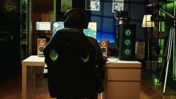 Man having fun playing videogames on desktop computer, chatting with teammates through headphones mic. Relaxed gamer communicating with friends through headset microphone during game at home, camera B video