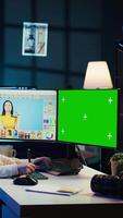 Vertical Photographer wearing headphones using advanced photo editing software on green screen monitor to upgrade images. Photo editor utilizing photographs retouching application on mockup PC, camera B video