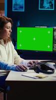 Vertical editor using editing software on green screen monitor to upgrade footage shot, commissioned by production teams outsourcing tasks. Freelancer videographer finishes project on mockup PC, camera B video