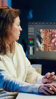 Vertical Portrait of happy editor merging raw clips and footage into high quality finished videos in production studio. Videographer using specialized software application and editing tools, camera A