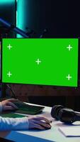 Vertical Photo editor working in independent production company using green screen monitor and graphic tablet. Photographer adjusting white balance on overexposed pictures on mockup desktop computer, camera B video