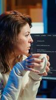 Vertical Portrait of engineer drinking coffee in the morning and futureproofing company network from downtimes. IT admin enjoying hot beverage while increasing data security, camera A video