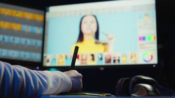 Photo editor using graphic tablet to retouch photographs with editing software on, zooming in to find spots that need correcting. Photographer in creative workplace adjusting images, camera B video