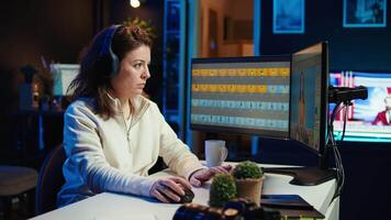 Freelancer editing professional photographs, working in home studio while enjoying music. Photo editor using headphones to listen favorite songs while using editing software, camera B video