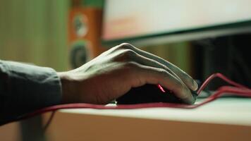 Gamer using keyboard and wired mouse to play videogames on desktop PC, close up shot. Man playing online game in front of monitor with computer peripherals at desk in apartment, camera A video