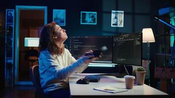 Admin listening music and writing lines of code filtering malicious traffic from cybercriminals attempting to steal company data. Woman wearing headphones while preventing malware, camera B video