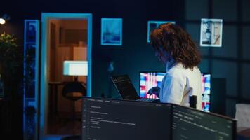 Woman walking in apartment designing and developing software applications using laptop. IT professional standing in living room, implementing and maintaining company systems, camera B video