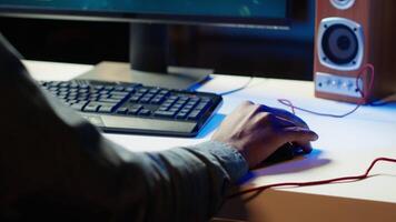 Keyboard and mouse used by gamer competing in online multiplayer videogame at home, close up. Focus on computer peripheral utilized by man playing on gaming PC in neon illuminated apartment, camera A video