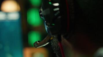 Man playing SF videogame on computer, having fun in neon lit apartment, close up. Gamer competing in online multiplayer game, using headphones to talk with teammates, camera A video