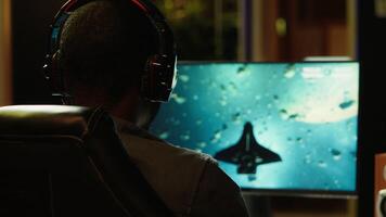 Gamer using headphones to discuss with mates while playing online SF videogame, close up. Close up enjoying futuristic coop spaceship flying arcade game with friends, chatting on internet, camera A video