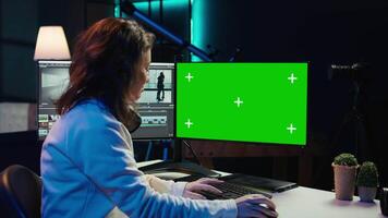 Freelancer works on isolated screen desktop computer on digital portfolio showcasing edited videos. editor selecting best clips using retouching application on chroma key display, camera B video