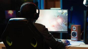 Pro gamer wearing headphones playing science fiction game. Content creator in gaming chair talking with audience on headset mic, filming tutorial on how to defeat enemies, camera A video