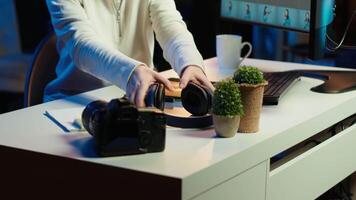 Photo editor editing images lighting and color balance, delivering visually appealing final product, listening to music. Freelancer wearing headphones, browsing through photographs, camera A video