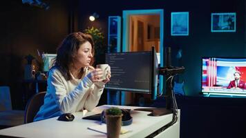 Portrait of happy computer engineer enjoying hot tea while implementing security measures to protect company systems and data. Joyful IT worker holding coffee mug and debugging code, camera B video