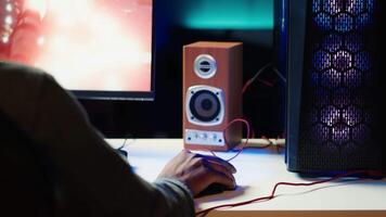 jugador utilizando teclado y ratón a jugar videojuego en juego de azar ordenador personal en neón iluminado departamento. jugador utilizando alto tecnología computadora periféricos a destruir enemigos, relajante a hogar, cámara un video