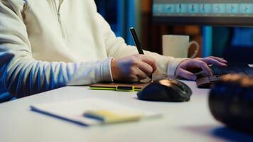 Photo editor using graphic tablet to edit images lighting, delivering visually appealing final product, listening podcasts. Freelancer wearing audio headset, browsing through photographs, camera A video