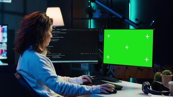 Freelancing admin using green screen computer monitors to filter malicious traffic from cybercriminals attempting to corrupt company data. IT expert in apartment working on mockup desktop PC, camera A video