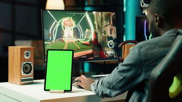 Chroma key tablet next to man playing high FPS singleplayer videogame with spaceship shooting lasers. Green screen device near gamer using crosshair to hit targets in SF game video