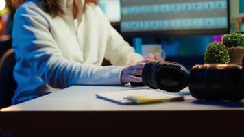 Freelancer editing images lighting and color balance, working in home studio while enjoying music. Photographer using headphones to listen favorite songs while using retouching software, camera A video