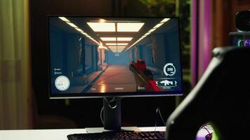 Shooting videogame on PC with neon lights illuminated components in empty apartment. Science fiction game on desktop PC monitor next to virtual reality glasses and computer peripherals video
