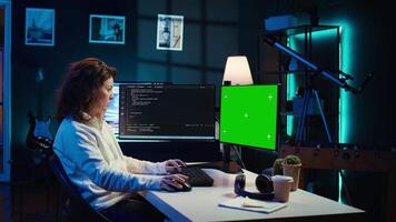 Freelancing admin using green screen computer monitors to filter malicious traffic from cybercriminals attempting to corrupt company data. IT expert in apartment working on mockup desktop PC, camera B video