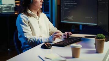 IT programmer listening music while fixing vulnerabilities in software compromising operating system. Cybersecurity expert wearing headphones and using PC to patch security exposures, camera A video