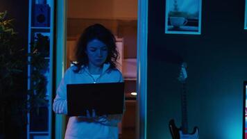 Computer scientist walking at home, developing software applications using laptop. IT professional standing in living room, implementing and maintaining company systems, camera B video