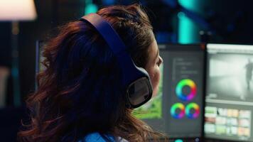 Freelancer adds sound effects to filmed footage, working in home studio. Post production specialist using headphones to test and improve audio quality using editing application, camera A video