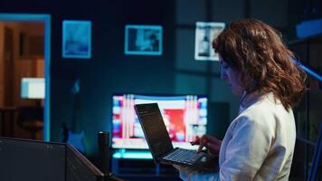 Developer doing software debugging using laptop, checking glitches in lines of code, upset about errors. Woman walking around home fixing coding issues using notebook device, camera B video