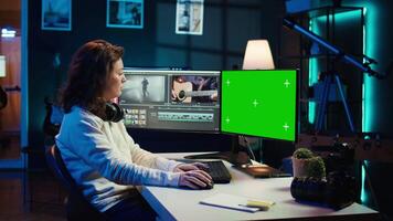 Videographer uses editing software on chroma key computer to assemble footage into final product. Woman color correcting clips on isolated screen PC to ensure project meets desired aesthetic, camera B video