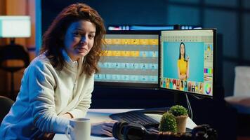 Cheerful photographer using retouching program to edit images on computer monitors. Portrait of smiling photo editor doing color grading on photographs in creative studio office, camera A video