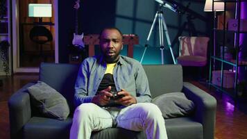 Gamer upset after losing while playing videogames on console system using controller. Man putting face in hands in frustration after being defeated playing games with gamepad, camera B video