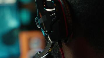 Streamer competing in intense online multiplayer videogame, streaming live at home, close up shot. Man playing on gaming PC, using headphones to discuss with viewers, camera A video
