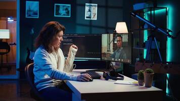 Woman doing software debugging helped by coworker in videocall, checking errors in lines of code. Programmer working from home fixing coding mistakes, assisted by colleague in teleconference, camera B video