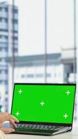 Vertical Business director working in her own office with green screen, looking at device display and developing a new project idea. Female entrepreneur empowered by corporate culture. Camera B. video