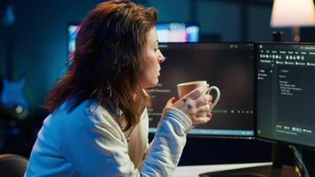 Portrait of happy computer engineer enjoying hot tea while implementing security measures to protect company systems and data. Joyful IT worker holding coffee mug and debugging code, camera A video