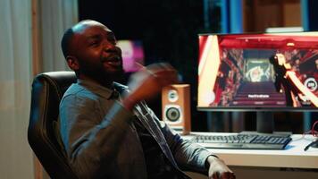 African american man teaching subscribers professional esports skills and how to play game. Media star on gaming chair chatting with viewers, filming gaming tutorial, camera A video