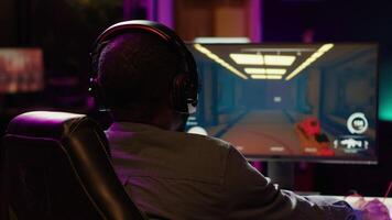 Pro gamer wearing headphones playing game, teaching audience esports needed skills. Content creator in gaming chair talking with audience, filming tutorial on how to defeat enemies, camera A video