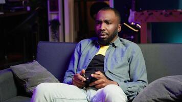 Gamer upset after losing while playing videogames on console system using controller. Man putting face in hands in frustration after being defeated playing games with gamepad, camera A video