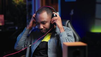 Man having fun playing videogames on PC, putting on headset to chat with teammates. Gamer battling rival players online, communicating with friends through headphones, camera A video