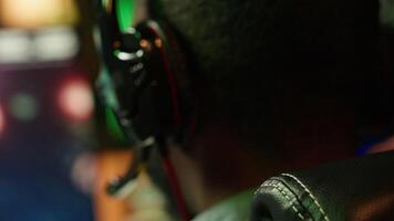 Man wearing headphones on while playing videogames at home to better immerse himself. Close up of player participating in online multiplayer esports tournament, fighting to defeat enemies, camera A video