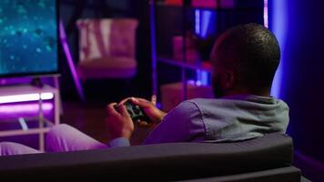 Man playing SF videogames on gigantic smart TV, relaxing after long day at work. Competitive gamer having fun on gaming console in apartment, piloting spaceship using controller, camera A video