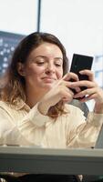 Vertical Business director texting messages and discussing about enterprise performance, sharing insight on updates and details. Young entrepreneur using her personal phone on social media. Camera A. video
