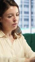 Vertical Stressed overwhelmed business leader working in discomfort with a headache, feeling overburdened and uncomfortable at the office. Female executive deals with anxiety and fatigue. Camera A. video