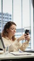 Vertical Business director texting messages and discussing about enterprise performance, sharing insight on updates and details. Young entrepreneur using her personal phone on social media. Camera B. video
