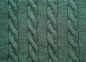 Texture of hand-knitted fabric made of green threads, cables knitting stitch pattern photo